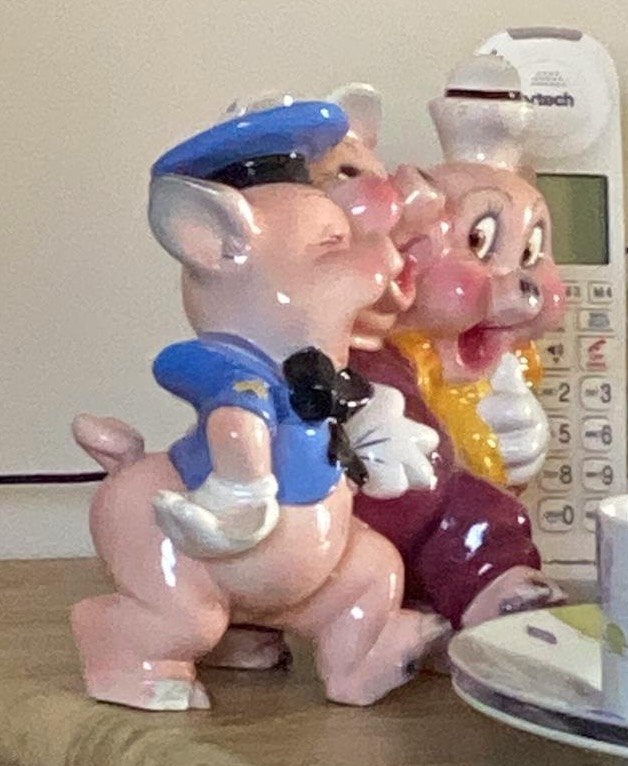 Roslyn’s three ceramic pigs, a policeman, a chef and a dancer, standing arm in arm on a wooden side table